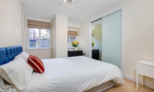 a bedroom with a large white bed with a red pillow at Nell Gwynn Chelsea Accommodation in London