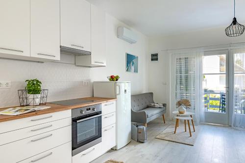 a kitchen with white cabinets and a chair in a room at Madarász Deluxe Vendégház in Balatonalmádi