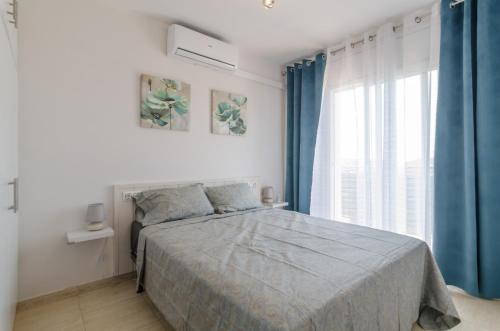 Schlafzimmer mit einem Bett mit blauen Vorhängen und einem Fenster in der Unterkunft Club Villamar - Santelmo in Lloret de Mar