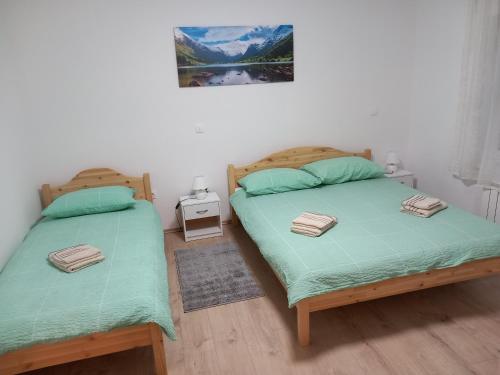 - une chambre avec 2 lits jumeaux et une photo sur le mur dans l'établissement Apartman Purga, à Fužine