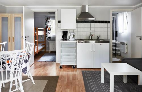 uma cozinha com armários brancos e uma mesa num quarto em First Camp Sjöstugan - Älmhult em Älmhult