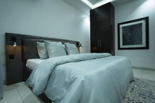 sypialnia z dużym łóżkiem z białą pościelą i poduszkami w obiekcie Palm Spring Luxury Apartment w mieście Port Harcourt