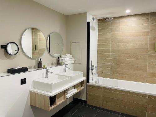a bathroom with a sink and a tub and a mirror at Citadines Eurometropole Strasbourg in Strasbourg