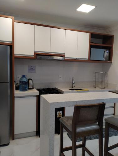 uma cozinha com armários brancos e uma bancada em Apartamento novo Gran Safira em Itapema