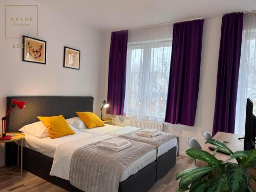 a bedroom with a large bed with purple curtains at Arche Residence Łódź in Łódź