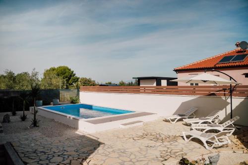 a backyard with a swimming pool and chairs and a house at Villa Frida in Sutomišćica
