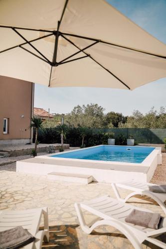 a pool with two chairs and an umbrella at Villa Frida in Sutomišćica