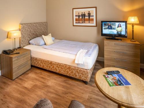 ein Schlafzimmer mit einem Bett und einem Tisch mit einem TV in der Unterkunft Sonnenresort Hüttmann in Norddorf