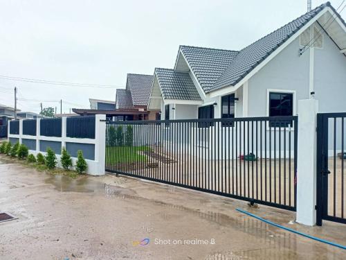 a white fence in front of a house at บ้านพักตากอากาศลำปาง in Lampang