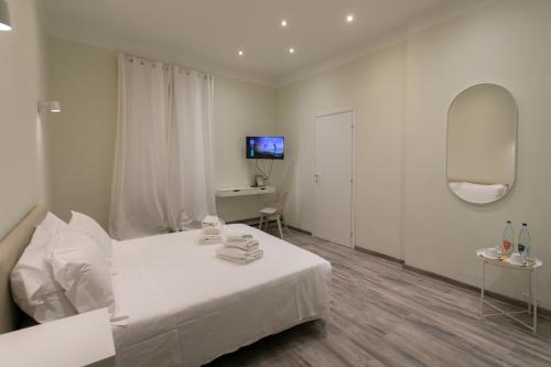 a white bedroom with a white bed and a television at Hotel L'Aretino in Arezzo