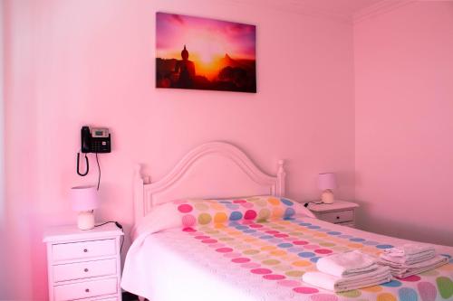 a pink bedroom with a bed and a picture on the wall at Residencial Princesa do Ave in Vila do Conde