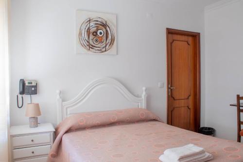 a white bedroom with a bed with a pink blanket at Residencial Princesa do Ave in Vila do Conde