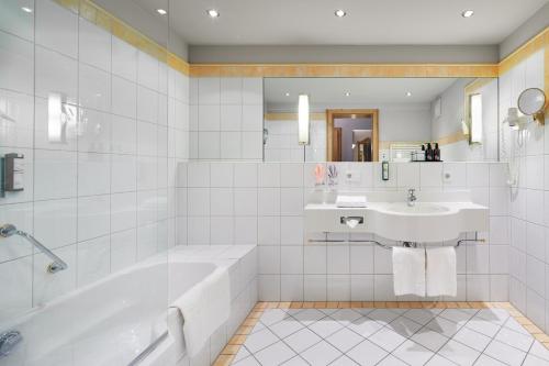 a white bathroom with a tub and a sink at Adler Inn Tyrol Mountain Resort SUPERIOR in Tux