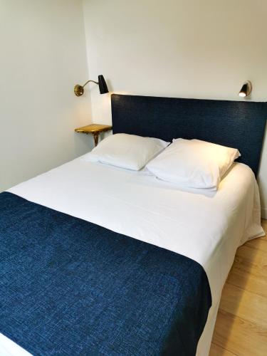 Elle comprend un grand lit avec des draps blancs et une couverture bleue. dans l'établissement LES MARIETTES, à La Rochelle