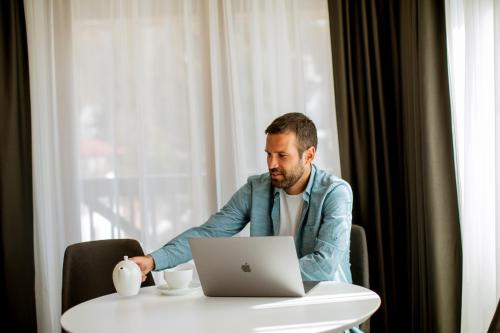 a man sitting at a table with a laptop computer at Apart & Spa Zoned in Kopaonik