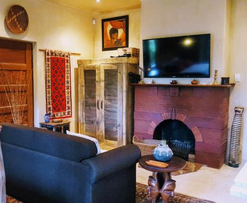 sala de estar con sofá y chimenea con TV en Frieden-Hof Guest Accommodation en Penhill