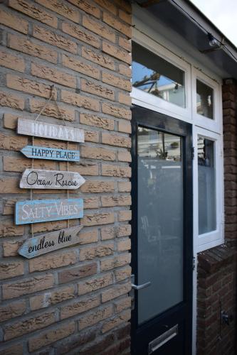 a brick wall with signs next to a door at ZeeBedStay in Noordwijk aan Zee