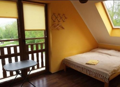 a bedroom with a bed and a table and a window at Leśne Klimaty in Polańczyk
