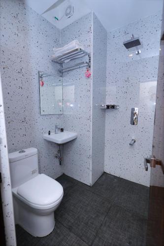 a bathroom with a white toilet and a sink at Hotel Vijaya Grand in Srikalahasti