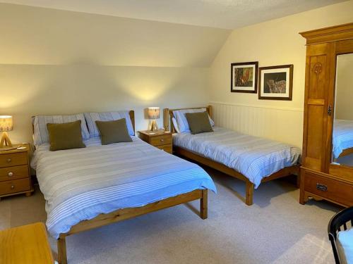 a bedroom with two beds and two night stands at Granite Cottage in Bridge of Cally