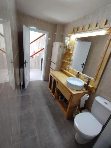 a bathroom with a toilet and a sink and a mirror at El Cortijo del Piron in Losana de Pirón