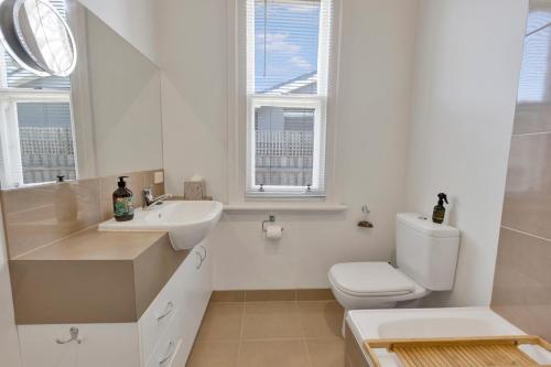 a white bathroom with a toilet and a sink at Cearc House in Bairnsdale