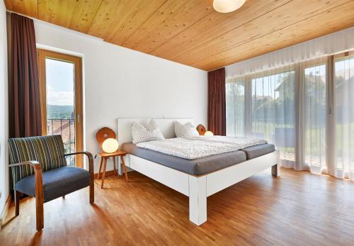 a bedroom with a bed and a chair and windows at Haus Arberblick Früchtl in Bodenmais