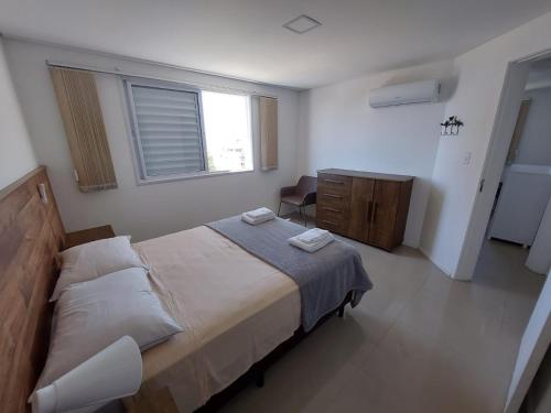 a bedroom with a bed and a desk and a window at Apartamento perfeito para descansar in Imbituba