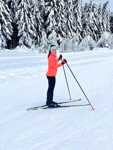 a young girl is standing on skis in the snow at Penzion Sen in Černá v Pošumaví