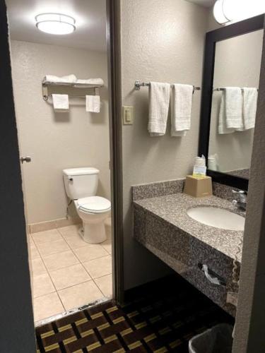 a bathroom with a toilet and a sink and a mirror at Days Inn by Wyndham Fort Wright Cincinnati Area in Fort Wright