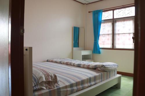 a bedroom with a bed with blue curtains and a window at ChillHouse24 @ DonMueang in Ban Don Muang