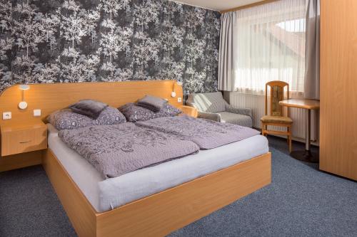 a bedroom with a large bed with a wooden headboard at Hotel Kobero in Říčany u Brna