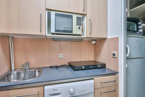 uma pequena cozinha com um lavatório e um micro-ondas em Cosy studio in the center of Clichy em Clichy