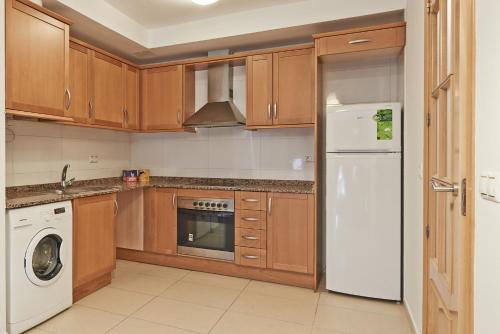 uma cozinha com armários de madeira e um frigorífico branco em Torredembarra em Torredembarra