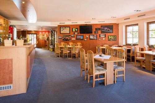 een restaurant met tafels en stoelen en een televisie bij Hotel Kobero in Říčany u Brna