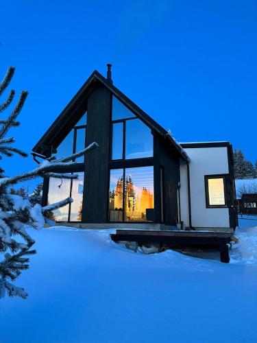 ein Blockhaus im Schnee mit Sonnenuntergang in der Unterkunft Cabana Neagră in Beliş