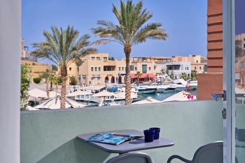 a table on a balcony with a view of a marina at Turtle's Inn Hotel in Hurghada