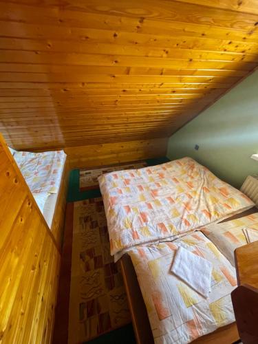 two beds in a room with wooden ceilings at Apartmán Králiky in Králiky