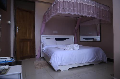 a bedroom with a white bed with a canopy at B10 Airport Lodge in Dar es Salaam
