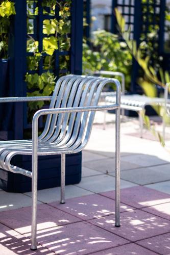 a metal bench sitting on top of a sidewalk at Hôtel Rosalie in Paris