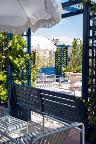 a group of benches and an umbrella on a patio at Hôtel Rosalie in Paris