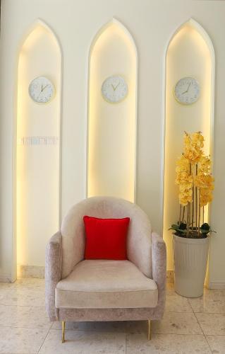 a chair with a red pillow in a room with two clocks at فندق المدينة القديمة Old Town Hotel in Nizwa