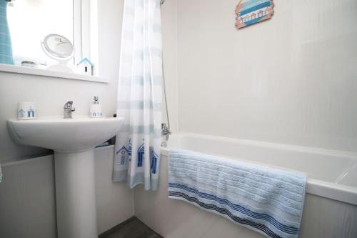 y baño blanco con lavabo, bañera y lavamanos. en 3 Bedroom family home Newport, Located next to M4, en Newport