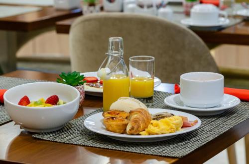 a table with a plate of breakfast food and orange juice at The 7 Hotel, Suites, Studios & Apartments in Lisbon