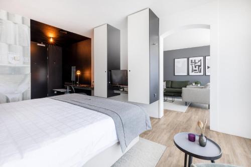 a bedroom with a white bed and a living room at Select Hotel Maastricht in Maastricht