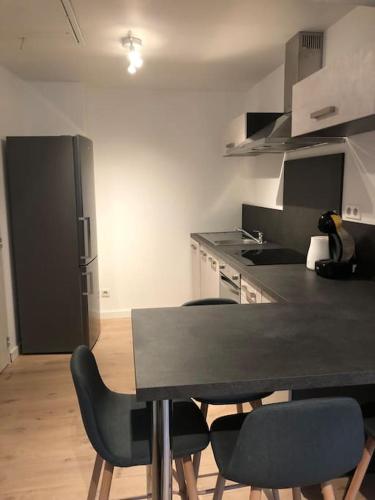 eine Küche mit einem Tisch und Stühlen sowie einem Kühlschrank in der Unterkunft Appartement moderne & lumineux 40m2 Centre Luxeuil in Luxeuil-les-Bains