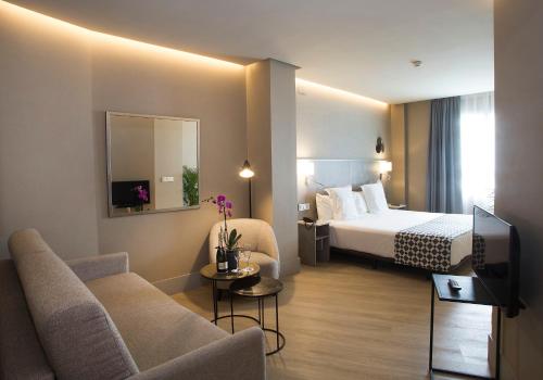 pokój hotelowy z łóżkiem i telewizorem w obiekcie Hotel América Sevilla w Sewilli