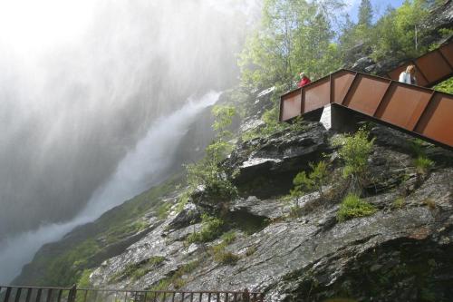 two people standing on a bridge over a waterfall at Sauda Fjord Camping in Saudasjøen