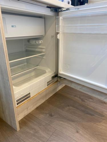 an empty refrigerator with its door open in a kitchen at Cosy North London 2 Bed Apartment in Woodside Park- Close to Station and Central London in Totteridge