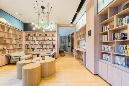 een bibliotheek met twee tafels en boekenplanken bij Atour Hotel Suzhou Wangting in Suzhou